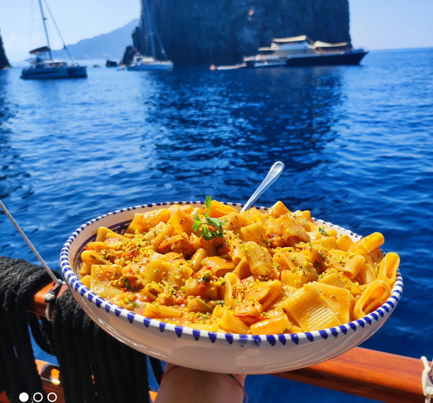 Un piatto di pasta servito a bordo, col mare dietro