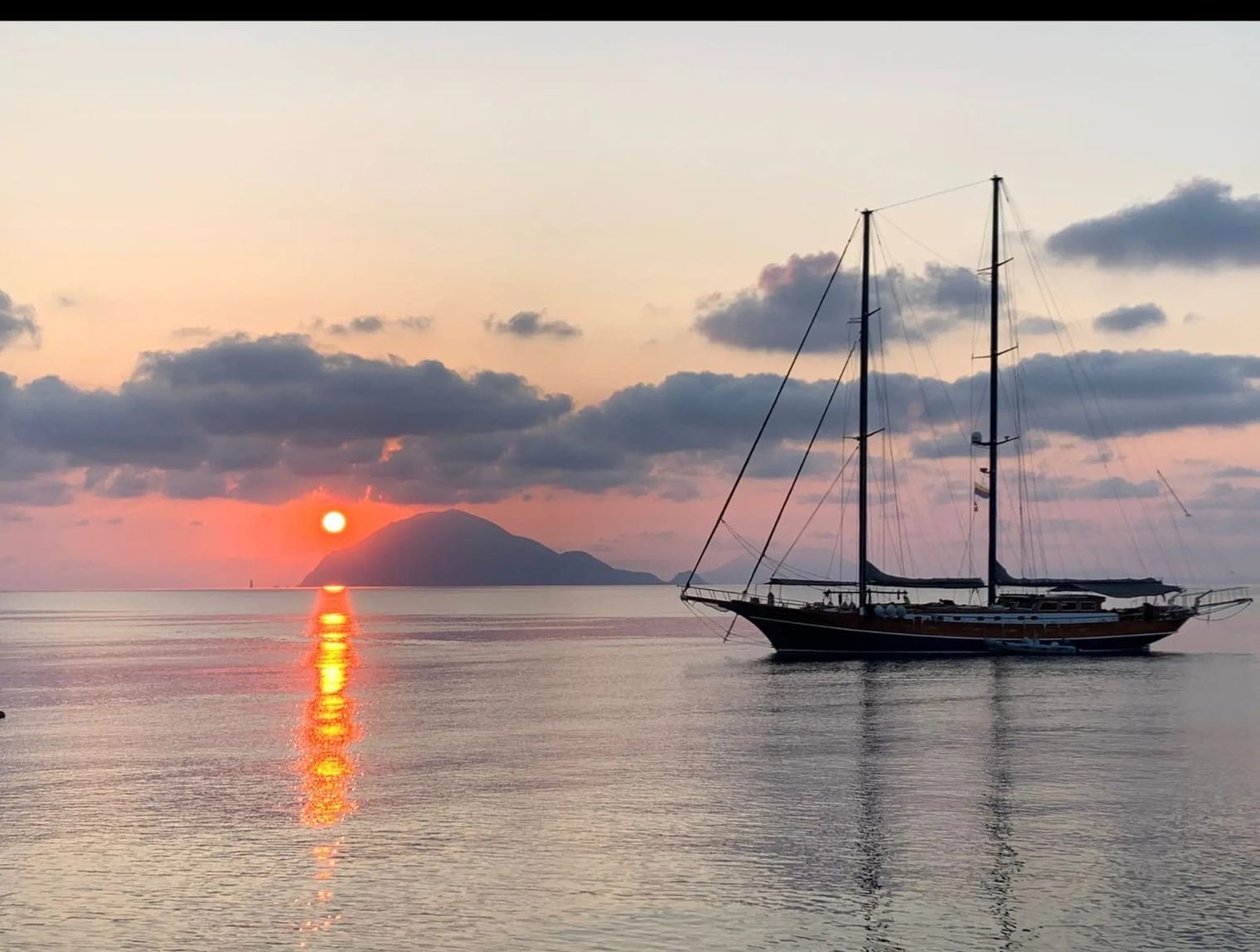 Il caicco alla fonda mentre il sole cala sul mare